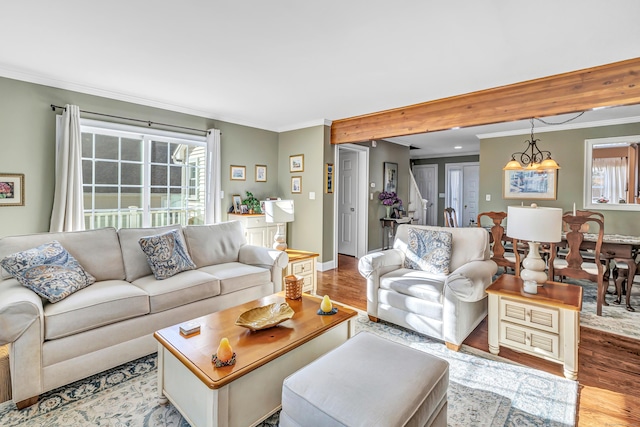 living room with light hardwood / wood-style flooring, ornamental molding, plenty of natural light, and an inviting chandelier