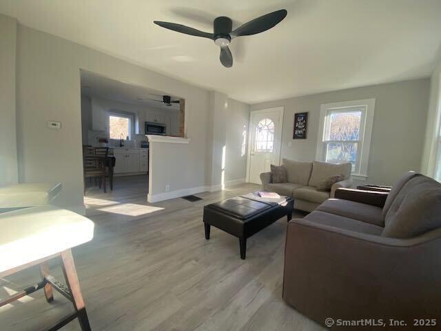 living room featuring ceiling fan and light hardwood / wood-style flooring