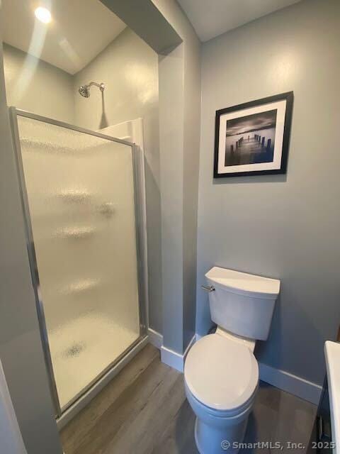 bathroom featuring hardwood / wood-style flooring, toilet, and a shower with door