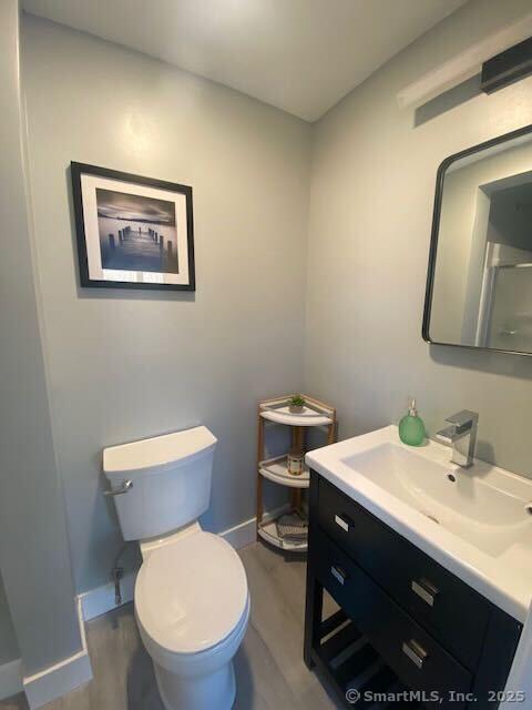 bathroom with wood-type flooring, vanity, and toilet