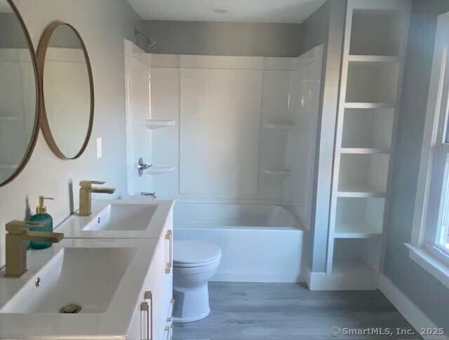 full bathroom featuring shower / bathing tub combination, vanity, built in shelves, toilet, and wood-type flooring