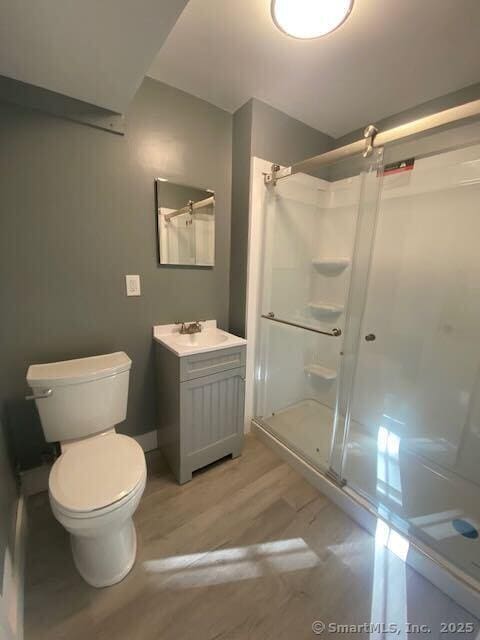 bathroom with hardwood / wood-style flooring, vanity, toilet, and walk in shower