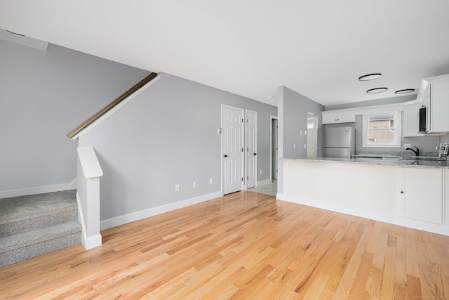 unfurnished living room with light hardwood / wood-style flooring and sink