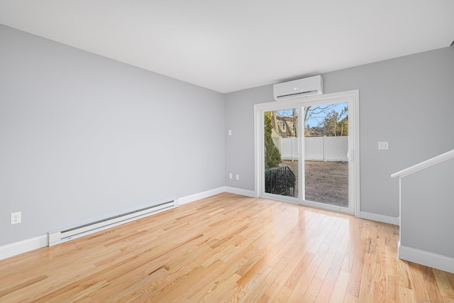 spare room featuring light hardwood / wood-style flooring, an AC wall unit, and a baseboard heating unit