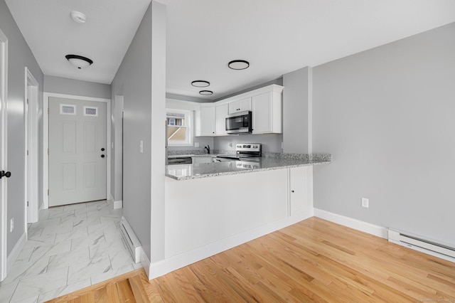 kitchen featuring kitchen peninsula, appliances with stainless steel finishes, baseboard heating, stone counters, and white cabinetry