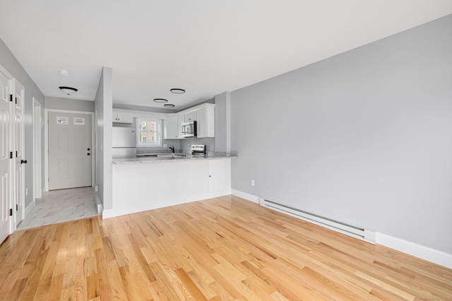 unfurnished living room featuring baseboard heating and light wood-type flooring