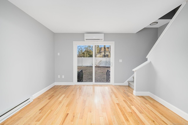 spare room with a wall mounted air conditioner, a baseboard radiator, and light hardwood / wood-style floors