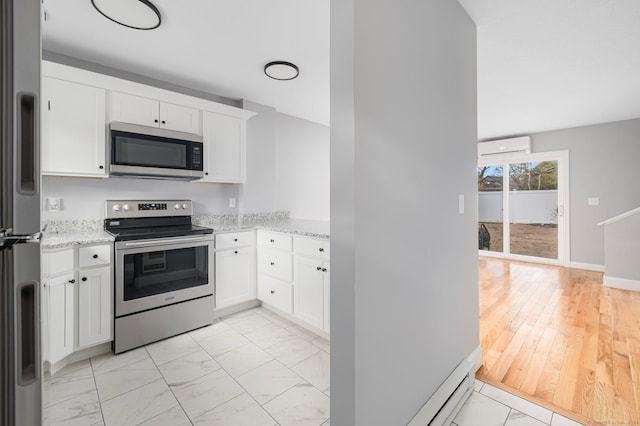 kitchen featuring light stone countertops, white cabinets, stainless steel appliances, and a wall mounted air conditioner