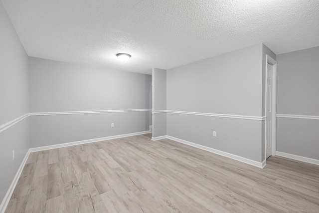 spare room with a textured ceiling and light hardwood / wood-style flooring