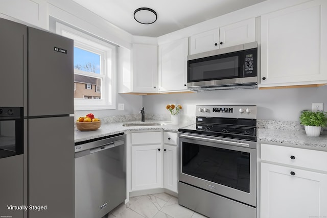 kitchen with light stone countertops, sink, white cabinetry, and stainless steel appliances