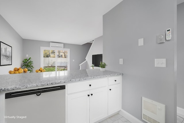 kitchen with stainless steel dishwasher, light stone counters, heating unit, an AC wall unit, and white cabinetry