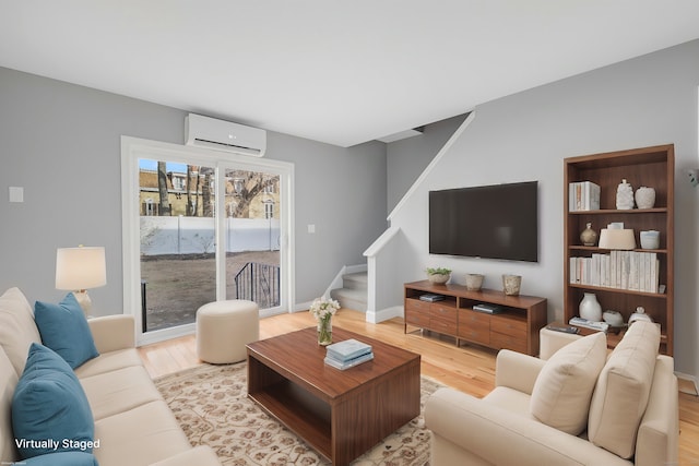 living room featuring a wall mounted air conditioner and light wood-type flooring