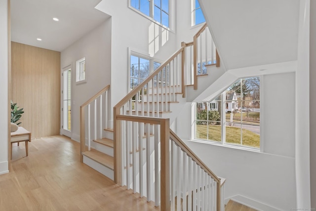 stairs with hardwood / wood-style floors and a high ceiling