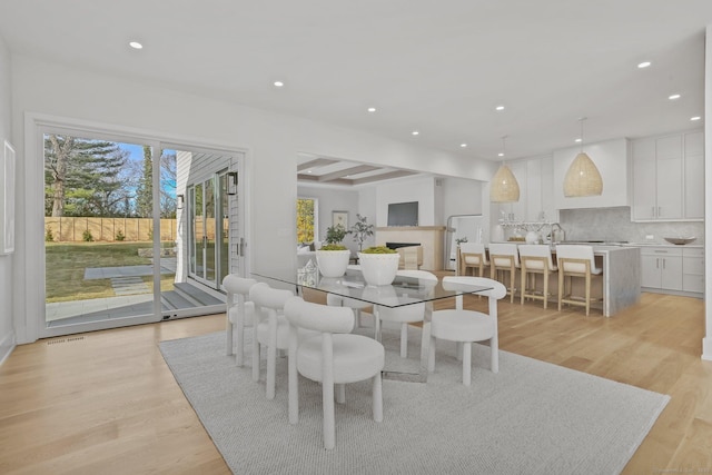 dining room featuring beamed ceiling and light hardwood / wood-style floors