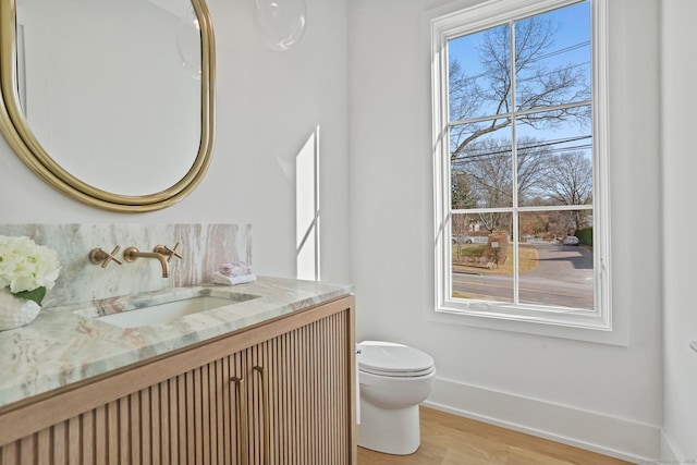 bathroom with hardwood / wood-style flooring, vanity, toilet, and a wealth of natural light