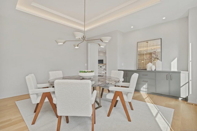 dining area featuring a tray ceiling, light hardwood / wood-style flooring, and a notable chandelier