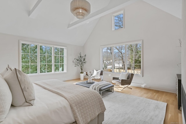 bedroom with beam ceiling, high vaulted ceiling, and light hardwood / wood-style flooring