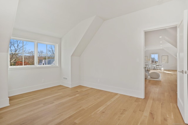 additional living space featuring light hardwood / wood-style floors and vaulted ceiling