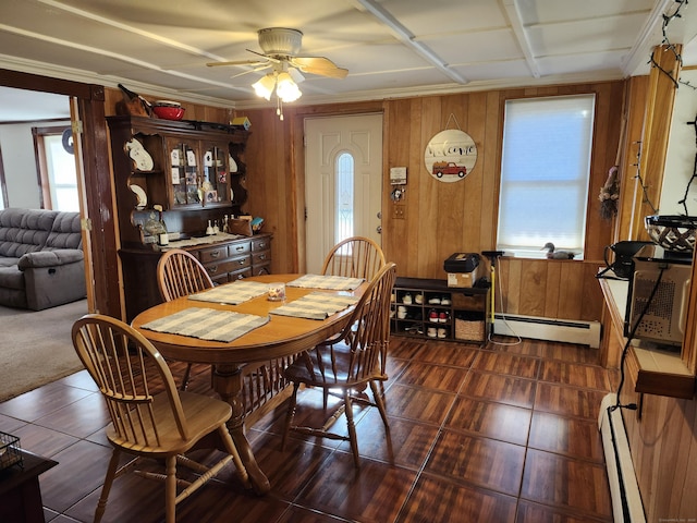 dining space with ceiling fan, wood walls, and a baseboard heating unit