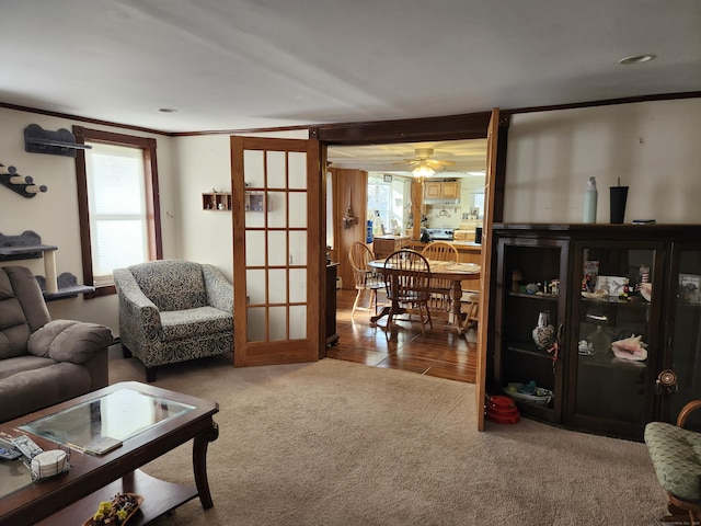 living room with carpet, ceiling fan, crown molding, and french doors