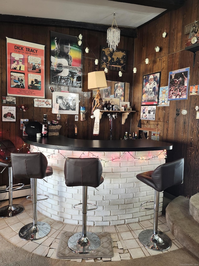 bar featuring an inviting chandelier and wooden walls