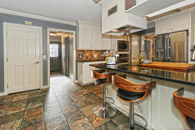 kitchen featuring white cabinets, appliances with stainless steel finishes, backsplash, and premium range hood