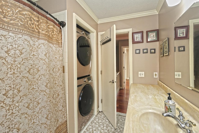 washroom featuring crown molding, sink, light tile patterned floors, a textured ceiling, and stacked washer / dryer