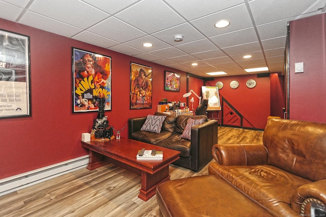 cinema room with light hardwood / wood-style flooring, a drop ceiling, and a baseboard heating unit