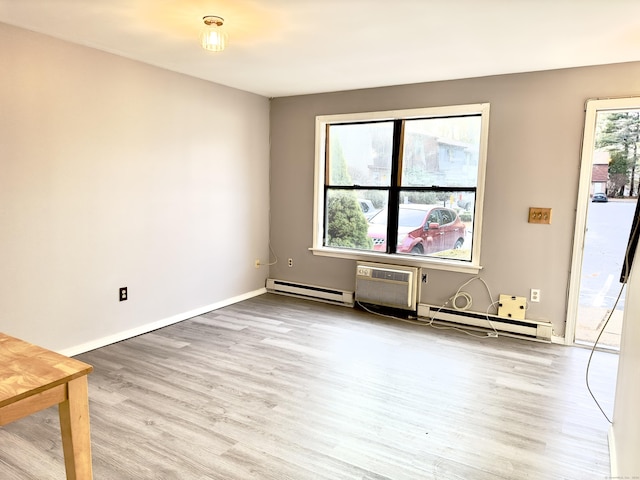 empty room featuring light wood-type flooring, a baseboard radiator, and a wall unit AC