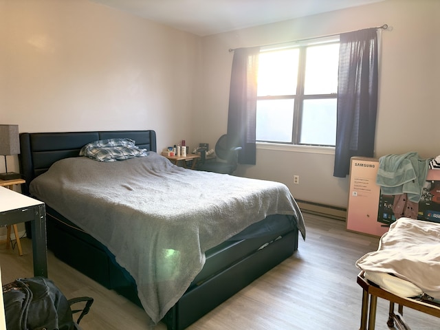 bedroom with light hardwood / wood-style flooring and a baseboard radiator