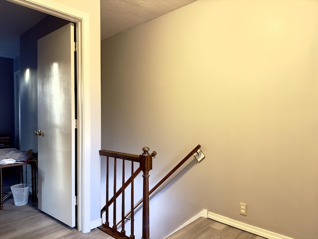 staircase with hardwood / wood-style flooring and a textured ceiling