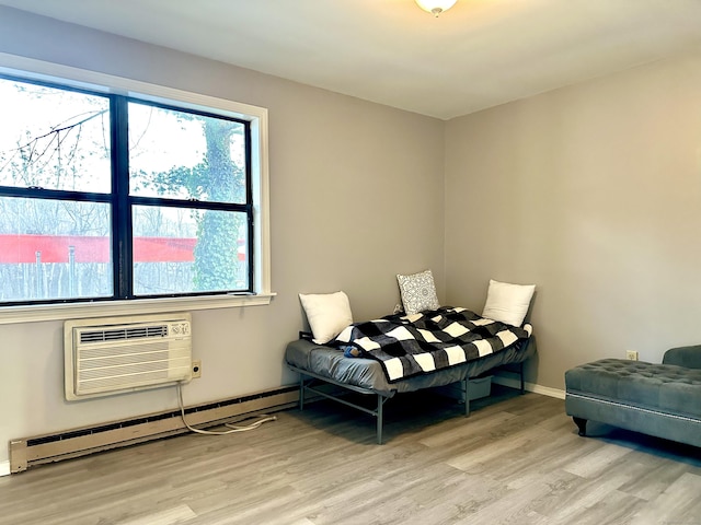 bedroom featuring light hardwood / wood-style flooring, a wall unit AC, and a baseboard radiator