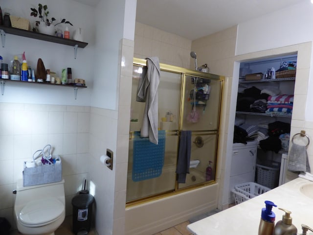 full bathroom featuring tile walls, toilet, tile patterned floors, enclosed tub / shower combo, and vanity