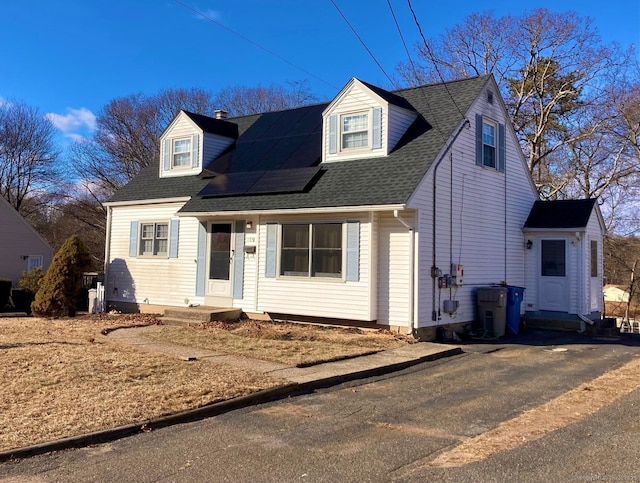 cape cod home featuring solar panels