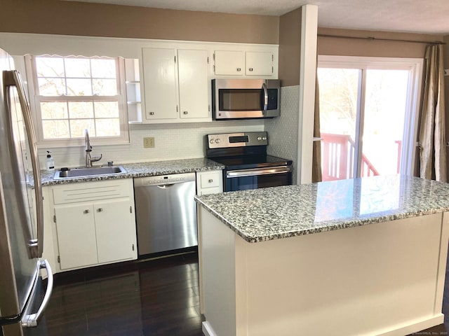 kitchen with white cabinets, light stone counters, sink, and appliances with stainless steel finishes