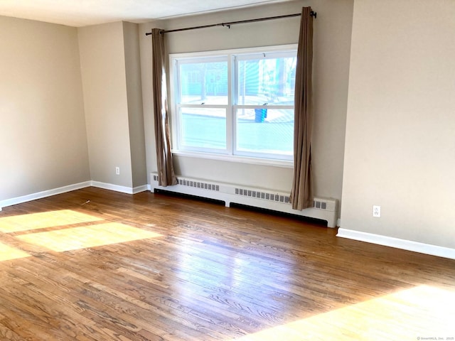 spare room with wood-type flooring and a baseboard heating unit