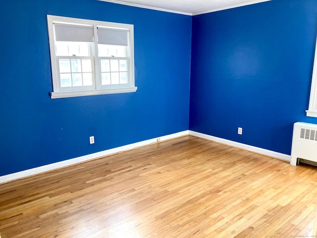 spare room with radiator heating unit and light wood-type flooring