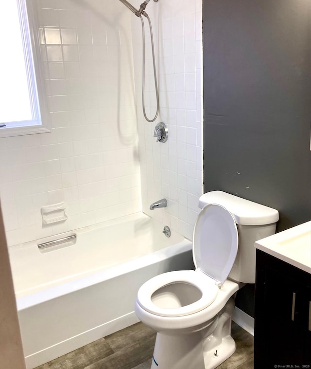 full bathroom featuring vanity, hardwood / wood-style floors, tiled shower / bath combo, and toilet