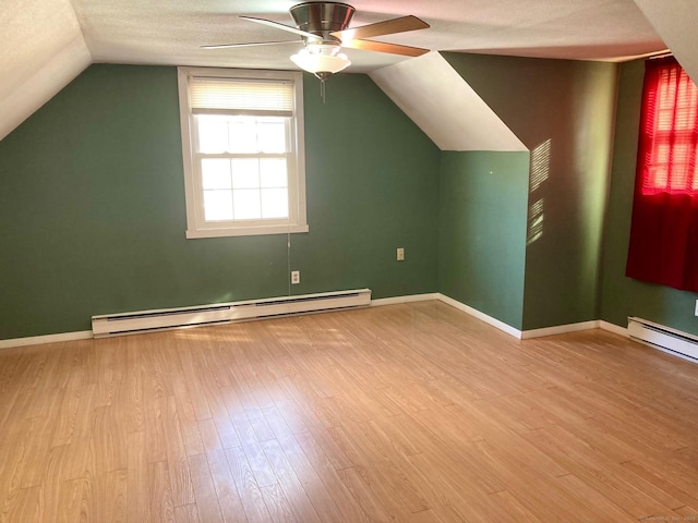 bonus room featuring a textured ceiling, ceiling fan, light wood-type flooring, and baseboard heating