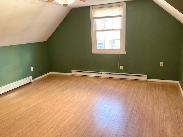 additional living space featuring ceiling fan, light wood-type flooring, baseboard heating, and vaulted ceiling