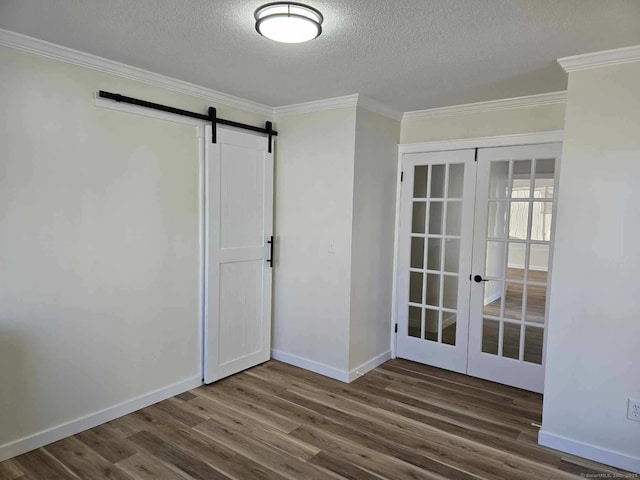 unfurnished room with a textured ceiling, dark hardwood / wood-style flooring, a barn door, and french doors