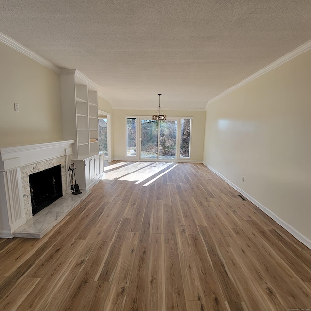 unfurnished living room with a textured ceiling, a premium fireplace, crown molding, and light wood-type flooring