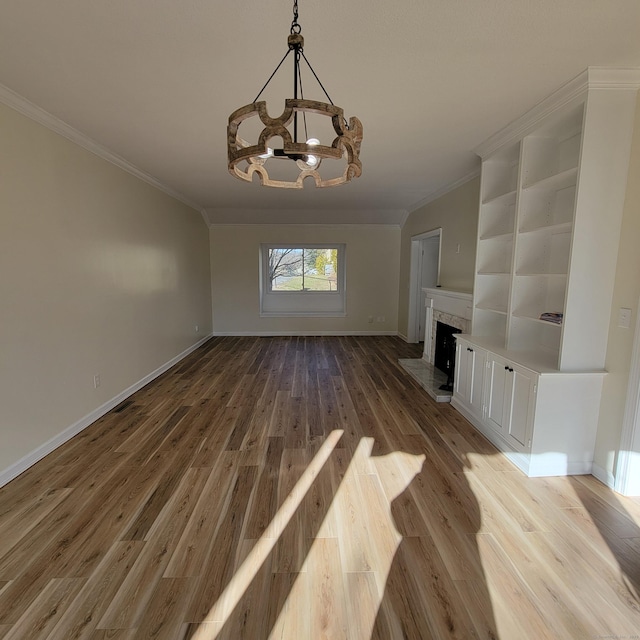 unfurnished living room with a premium fireplace, ornamental molding, light hardwood / wood-style floors, and a notable chandelier