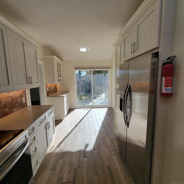 kitchen featuring decorative backsplash, white cabinetry, stainless steel fridge with ice dispenser, and electric range