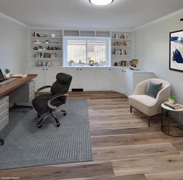 office space with a textured ceiling, built in shelves, crown molding, and light wood-type flooring