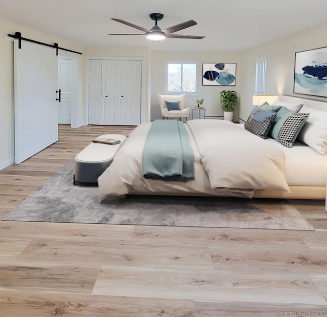 bedroom featuring ceiling fan, a barn door, a closet, and hardwood / wood-style flooring