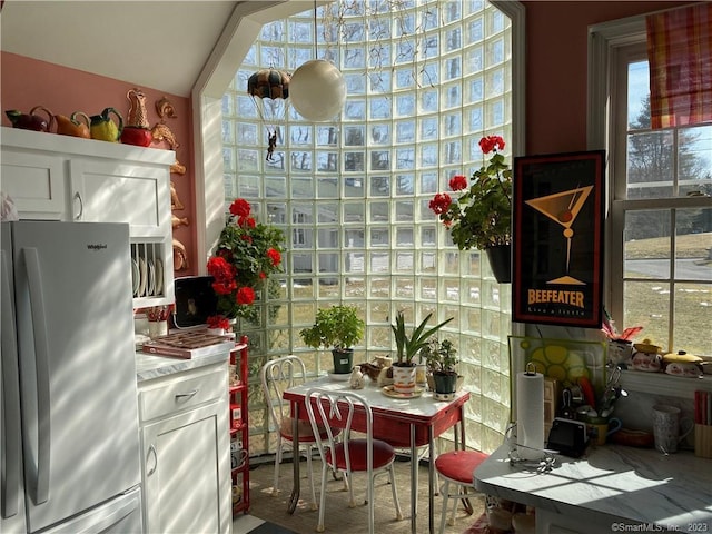 kitchen featuring white cabinets, lofted ceiling, stainless steel fridge, and a healthy amount of sunlight