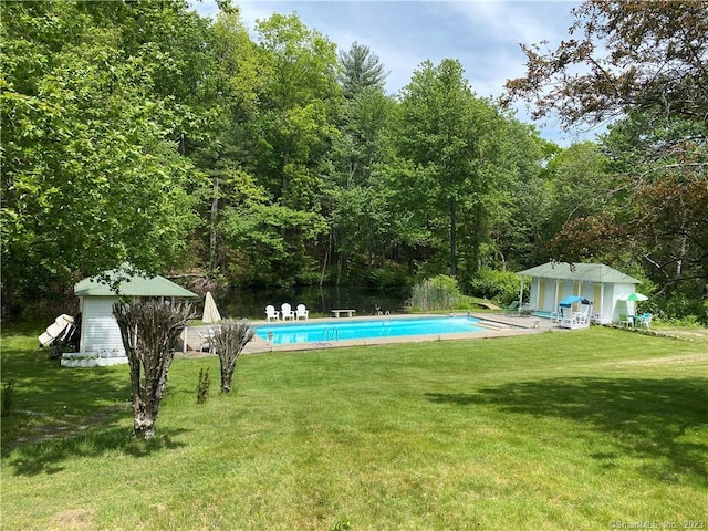 view of pool featuring a lawn and an outbuilding