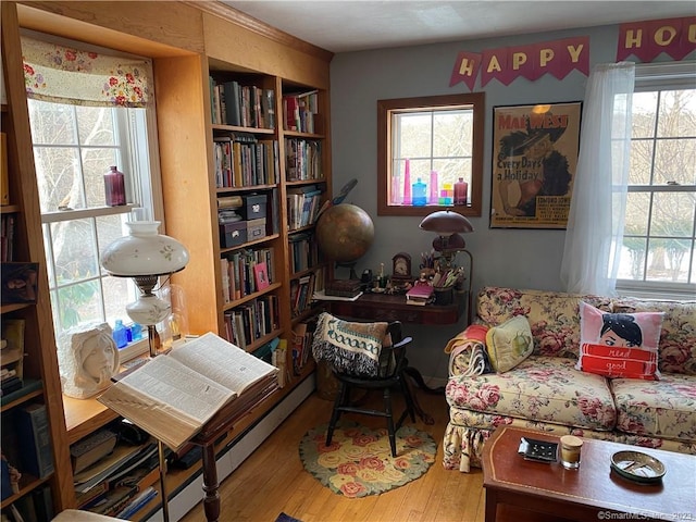 living area featuring a healthy amount of sunlight, a baseboard heating unit, and wood-type flooring