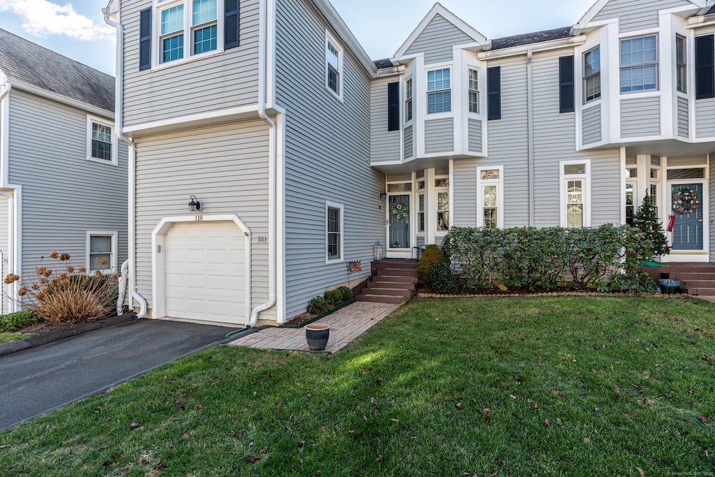 townhome / multi-family property with a front lawn and a garage